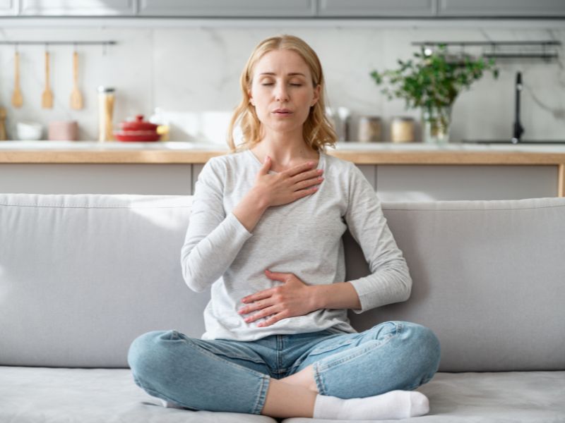 Woman taking deep, calming breaths representing Pillar 6 of the of the  7 pillars of holistic skincare, Stress Management.